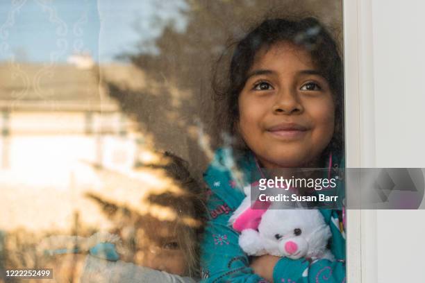 young girl stares out window with easter bunny