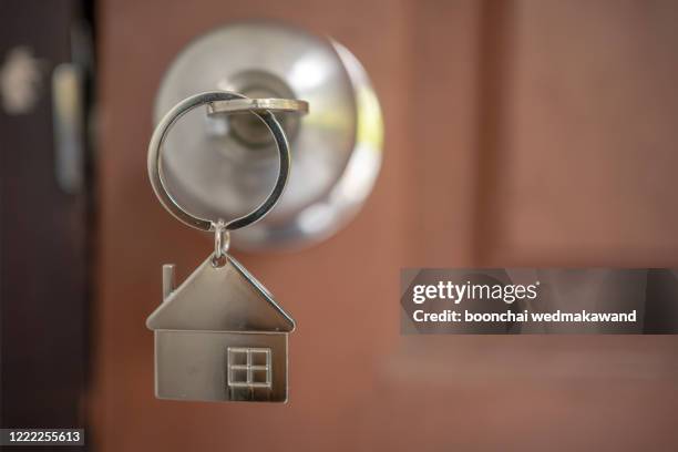 silver house key in a door - housing loan stockfoto's en -beelden