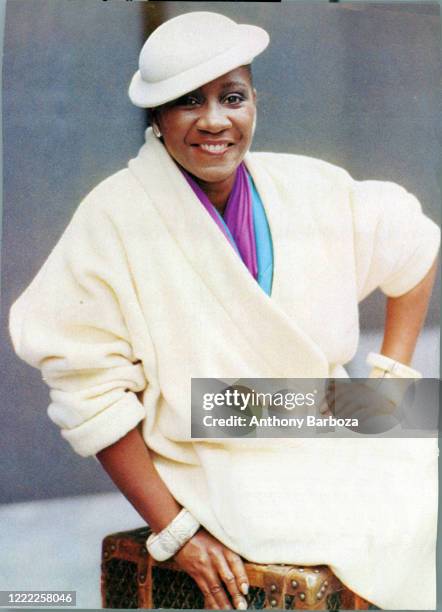 Portrait of American singer and actress Patti LaBelle , dressed in a white coat, as she sits perched upon a steamer truck, 1980s.