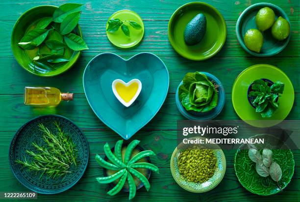 de inventaris van het huis allen in groene serviesplaten met vegetarisch voedsel en hartvorm olijfolie op groen - creative food stockfoto's en -beelden