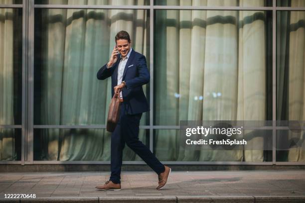 talking on the go: smiling businessman making a phone call on the way to the office - wide angle lens stock pictures, royalty-free photos & images