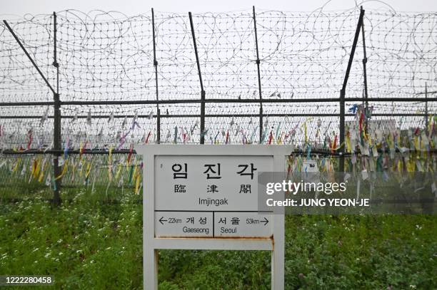 Sign showing the distance to North Korea's Kaesong city and South Korea's capital Seoul is seen in front of a military fence decorated with ribbons...