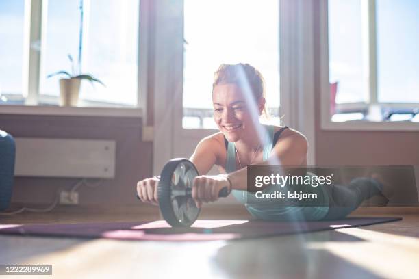 sports woman is doing ab roller whit leggs in the air. - abs fotos imagens e fotografias de stock