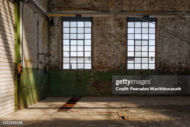 interior view of empty open floor of abandon former workshop factory with damaged building elements, wall, windows and ceilings, with nobody. - 工業団地 ストックフォトと画像