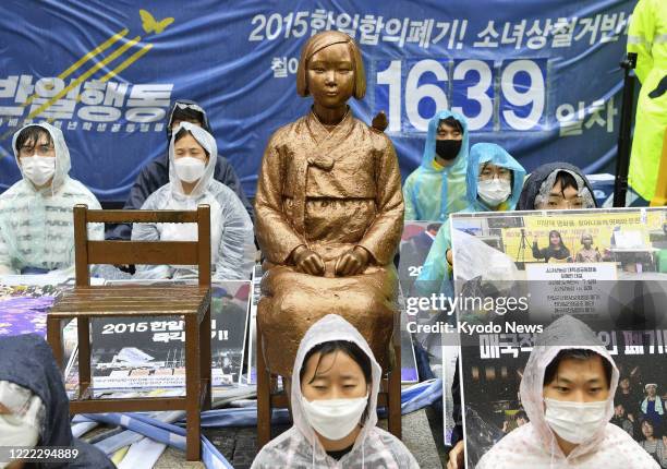 Members of a South Korean reformist student group sit around a statue symbolizing "comfort women," forced to work at the Japanese military's wartime...