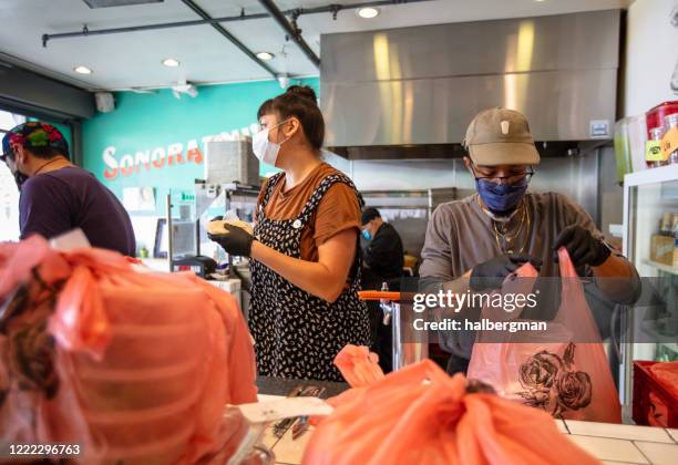 restaurant personeel dragen maskers en handschoenen aan het werk tijdens covid-19 lockdown - tacokraam stockfoto's en -beelden