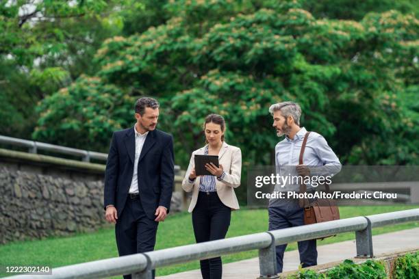 businesspeople using digital tablet in public park - business park stockfoto's en -beelden