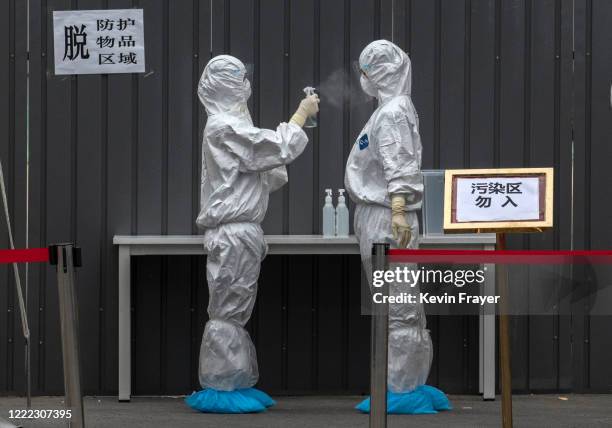 Chinese epidemic control workers wear protective suits as they disinfect each other after performing nucleic acid swab test for COVID-19 on citizens...