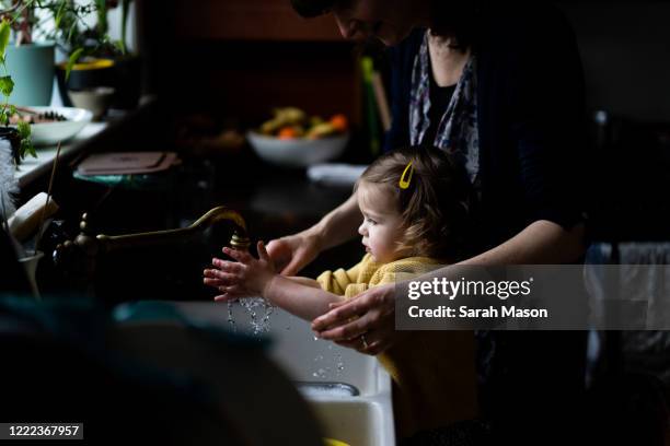 mother and little girl washing hands - パンデミック ストックフォトと画像