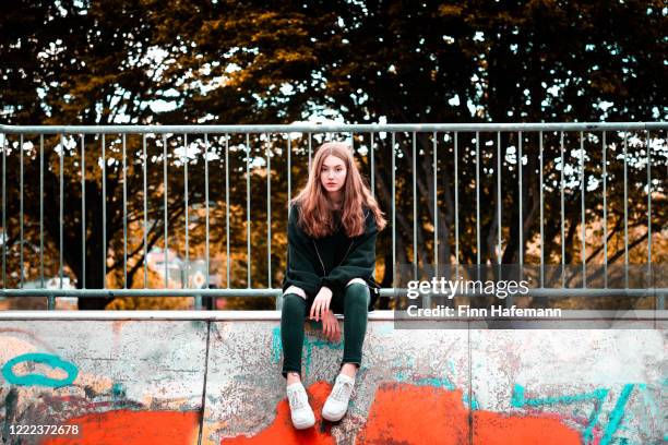 fashionable teenage girl sitting on urban concrete wall - boring portrait imagens e fotografias de stock