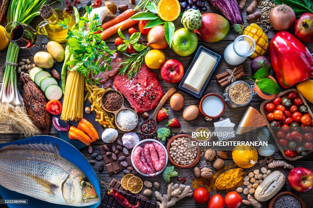 Varied food carbohydrates protein vegetables fruits dairy legumes on wood