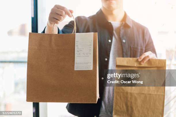 man delivering takeaway food at the front door - food delivery fotografías e imágenes de stock