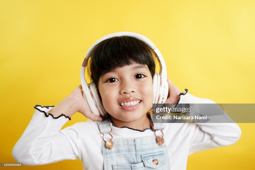 Happy Asian child girl listen the music song in wireless headphone from mp3 player technology. relaxation and music lover concept.