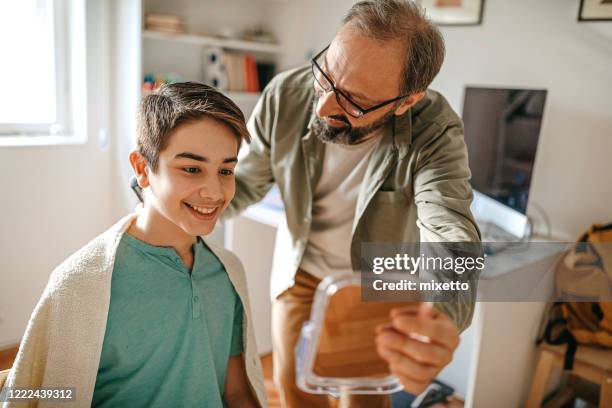 showing haircut result to son in mirror - teenage boy shave imagens e fotografias de stock