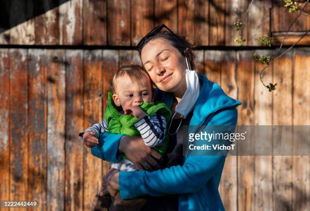 jonge moeder en haar baby die zonlicht in openlucht in de tijd van pandemie verzamelen - vitamin d stockfoto's en -beelden