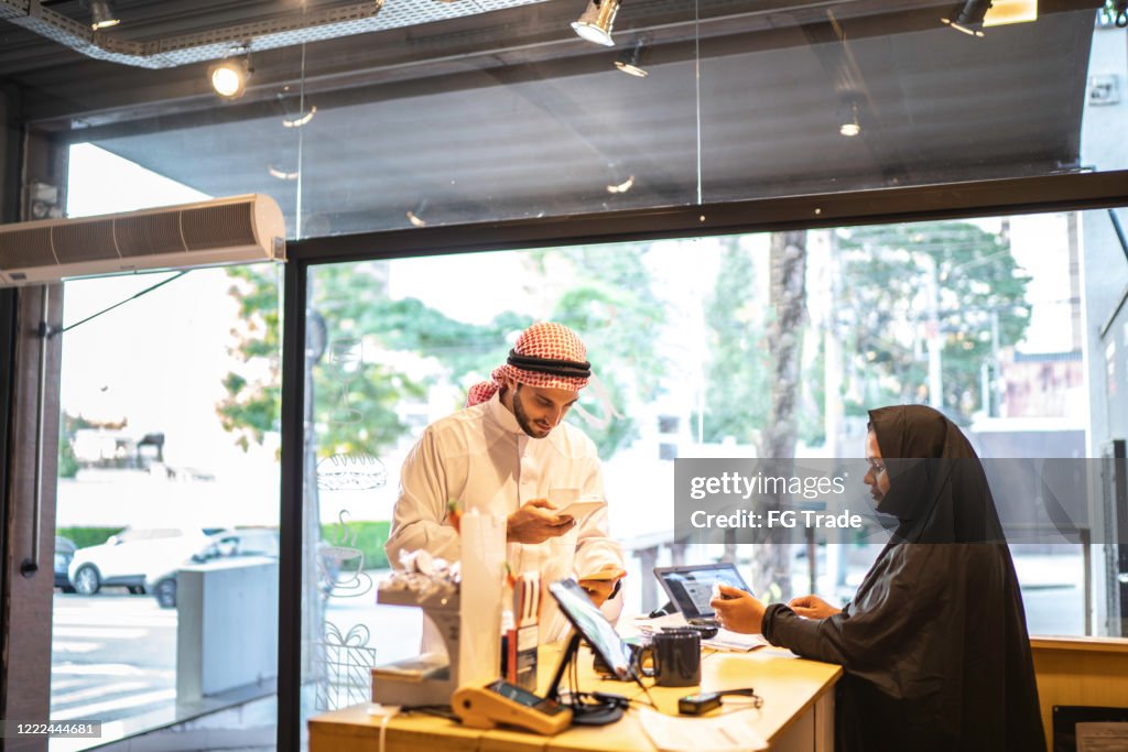 Arab Middle East man doing mobile payment at convenience store