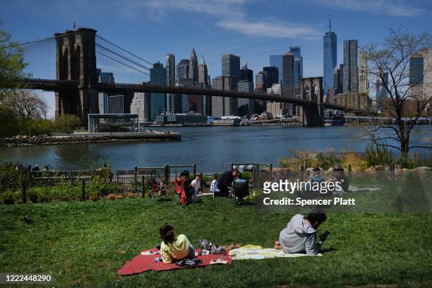 People keep their personal distance as they enjoy a spring afternoon in Brooklyn Bridge Park on May 02, 2020 in the Brooklyn borough of New York...
