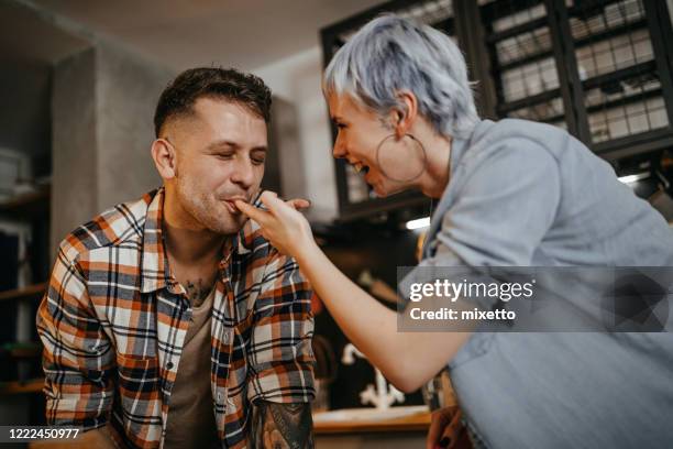 pareja degustación de alimentos en la cocina doméstica - finger in mouth fotografías e imágenes de stock