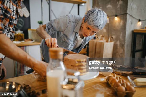couple making cake at domestic kitchen - two layer cake stock pictures, royalty-free photos & images