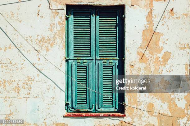 closed green window shutters against weathered wall - shabby chic stockfoto's en -beelden