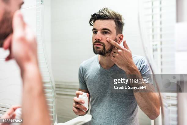 man applying moisturizer - acnes stock pictures, royalty-free photos & images