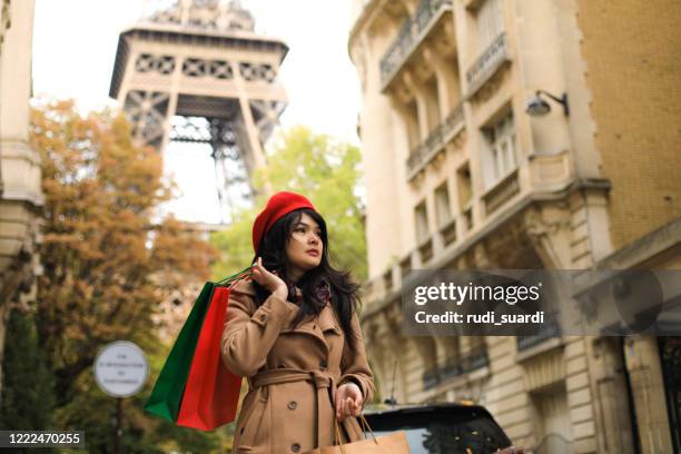 de vrolijke vrouw van azië loopt in de stad. ze houdt een boodschappentas vast en gebruikt haar smartphone. - paris street woman stockfoto's en -beelden