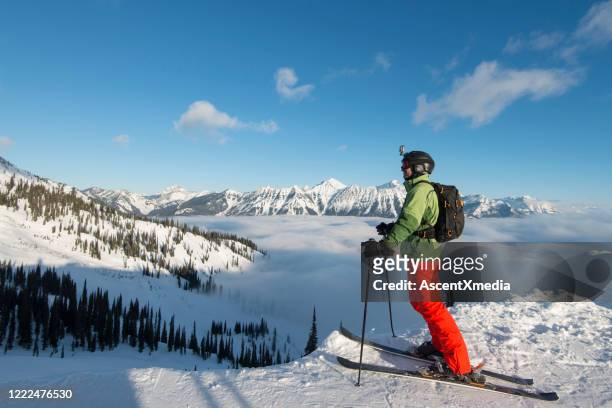 高山滑雪者在霧庫、山脈和山谷上方放鬆 - green coat 個照片及圖片檔
