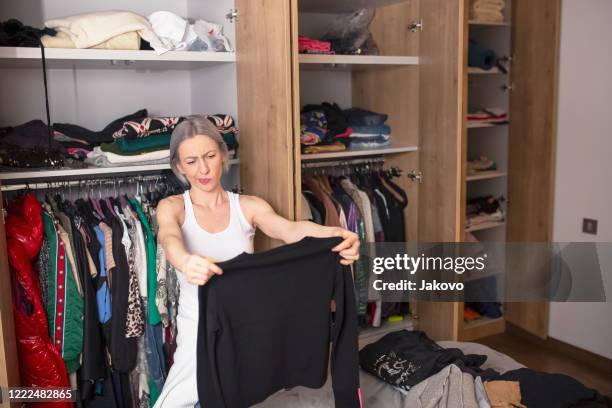 frau reorganisiert ihre garderobe in ihrem schlafzimmer - clothes wardrobe stock-fotos und bilder