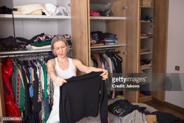 woman reorganizing her wardrobe in her bedroom - arrumado imagens e fotografias de stock