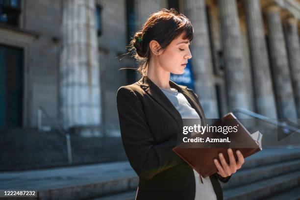 brunette female law student reading at university entrance - law book stock pictures, royalty-free photos & images