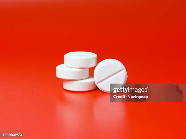 circular white pills on red background - acetylsalicylizuur stockfoto's en -beelden