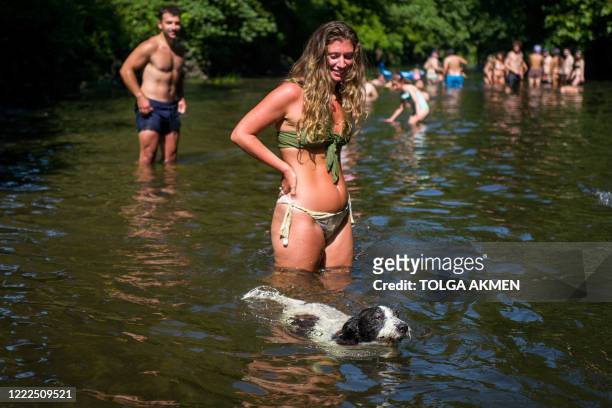 Sun-seekers cool off in the water and sunbathe on the riverbank at Hackney Marshes in east London on June 24 as temperatures reached 31 degrees C at...