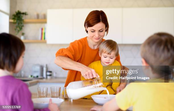 mother with three small children in the morning at home, having breakfast. - milk jug stock pictures, royalty-free photos & images