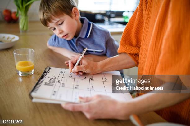 unrecognizable mother with small son indoors in kitchen, planning. - planning agenda foto e immagini stock