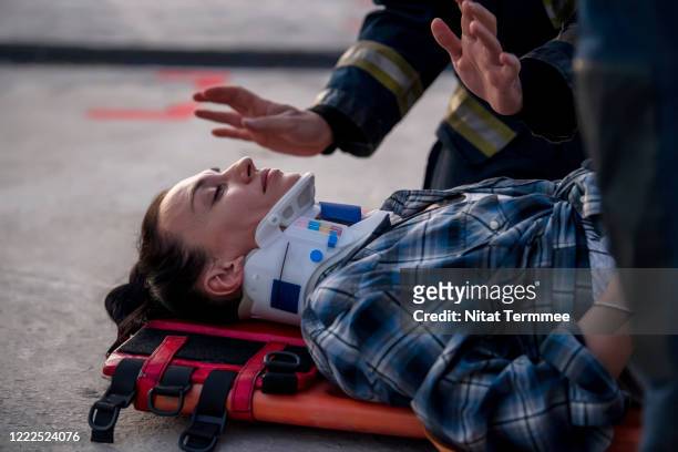 rescue worker examining a woman lying on road. firefighters rescue a woman laying down on emergency stretcher the road after an car accident or a burning building. - burn injury fotografías e imágenes de stock