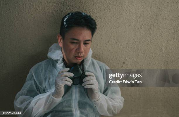 an asian chinese mid adult man resting and taking off protective wear after disinfection process, exhausted with marks on his face