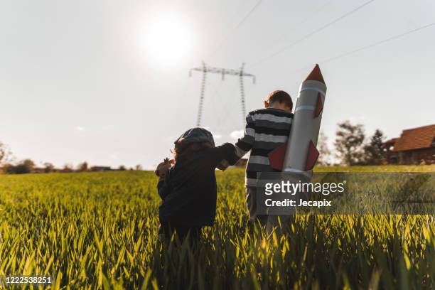 cute brother and sister playing in grass field on sunny day - toy rocket stock pictures, royalty-free photos & images