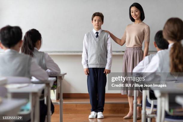 young chinese teacher introducing a new classmate in classroom - the new school stock pictures, royalty-free photos & images