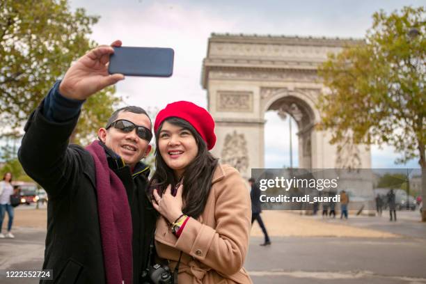 cheerful asian traveler are walking  in the city. she is holding a shopping bag  and using her smart phone. - honeymoon europe stock pictures, royalty-free photos & images