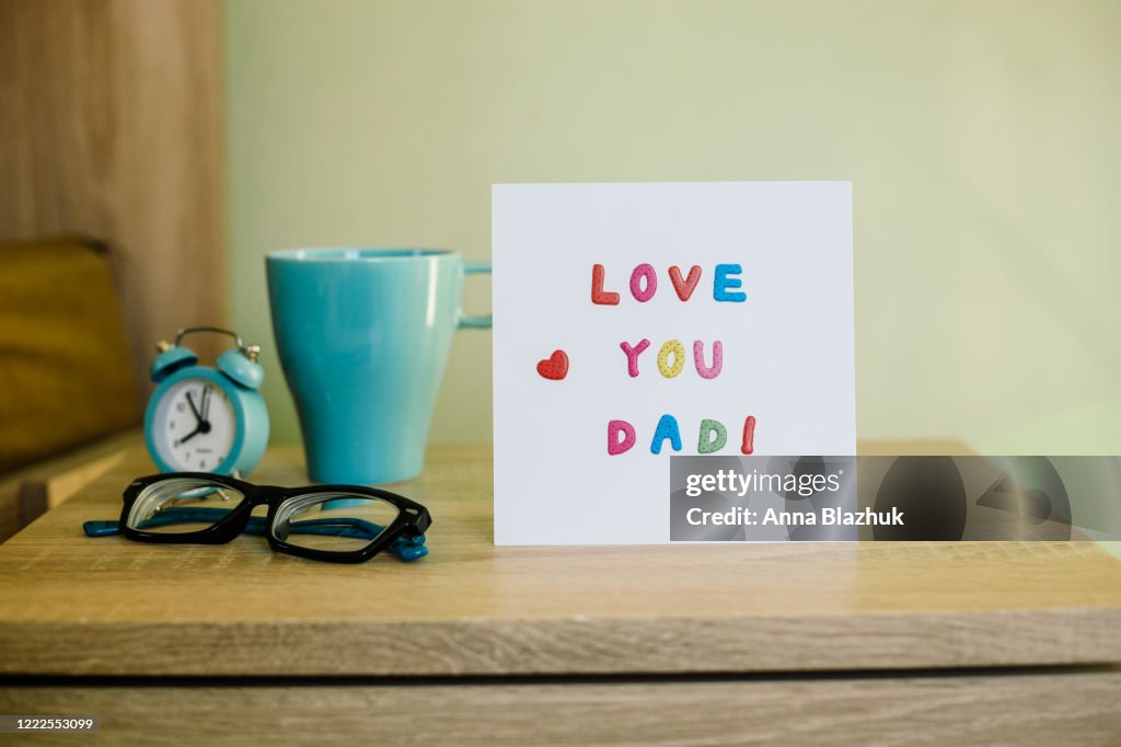 Greeting Card for Happy Father's Day, on the bed, paper white sheet with text Love You Dad and heart, colorful letters