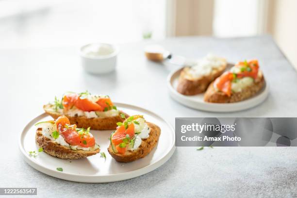 bruschetta au saumon, fromage caillé et concombre sur pain grillé dans un style haute clé sur fond blanc. - tartine photos et images de collection