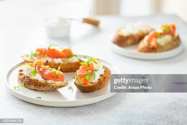 bruschetta con salmón, queso cuajada y pepino en tostado en estilo clave sobre fondo blanco. - aperitivo plato de comida fotografías e imágenes de stock