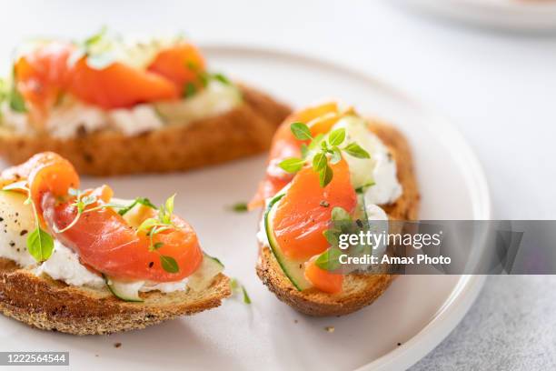 bruschetta met zalm, wrongelkaas en komkommer op toost in hoge zeer belangrijke stijl op witte achtergrond. - avocado toast white background stockfoto's en -beelden