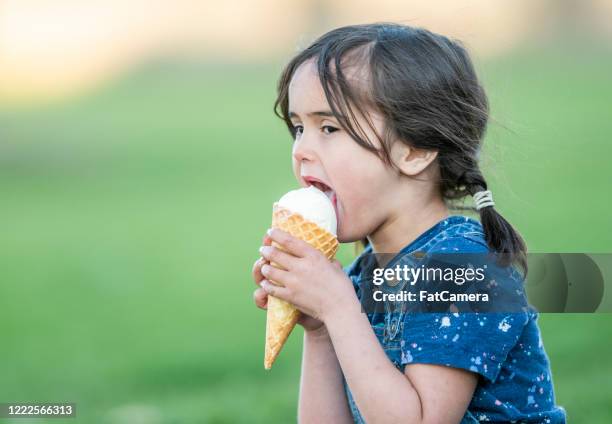 young child enjoys ice cream - girl eating messy ice cream cone stock pictures, royalty-free photos & images