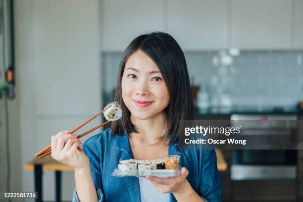 young woman eating takeaway sushi rolls - woman sushi stock-fotos und bilder