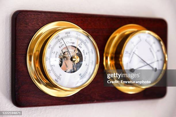 mechanical weather station on a wooden plate mounted on the wall. - barometer stock-fotos und bilder