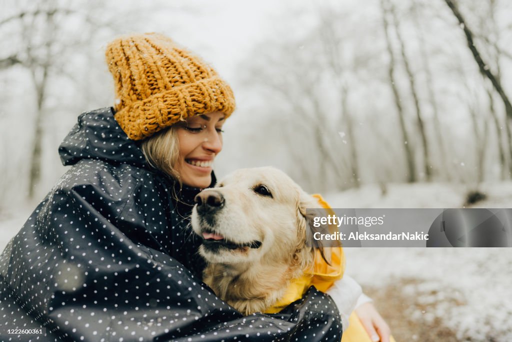 Glimlachende vrouw en haar hond in een sneeuwdag