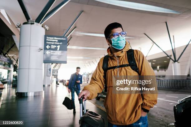 asian man wearing mask at the airport - coronavirus travel stock pictures, royalty-free photos & images