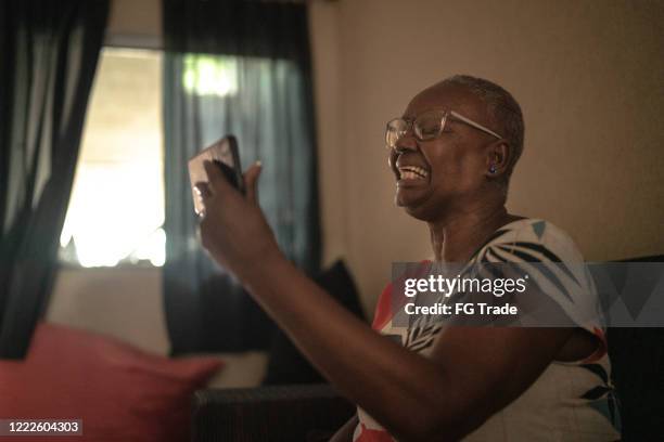 senior woman doing a video call with mobile phone at home - one woman only videos stock pictures, royalty-free photos & images