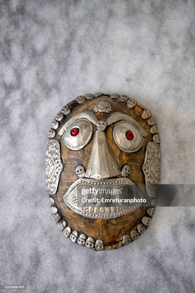 Decorative mask made from metal and turtle shell on a marble table.